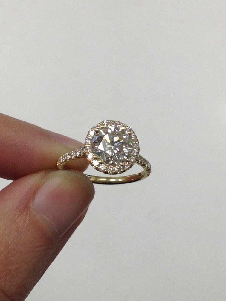 Round halo engagement rings on finger