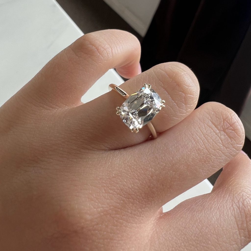 Elongated Antique cushion cut solitaire diamond ring on hand 