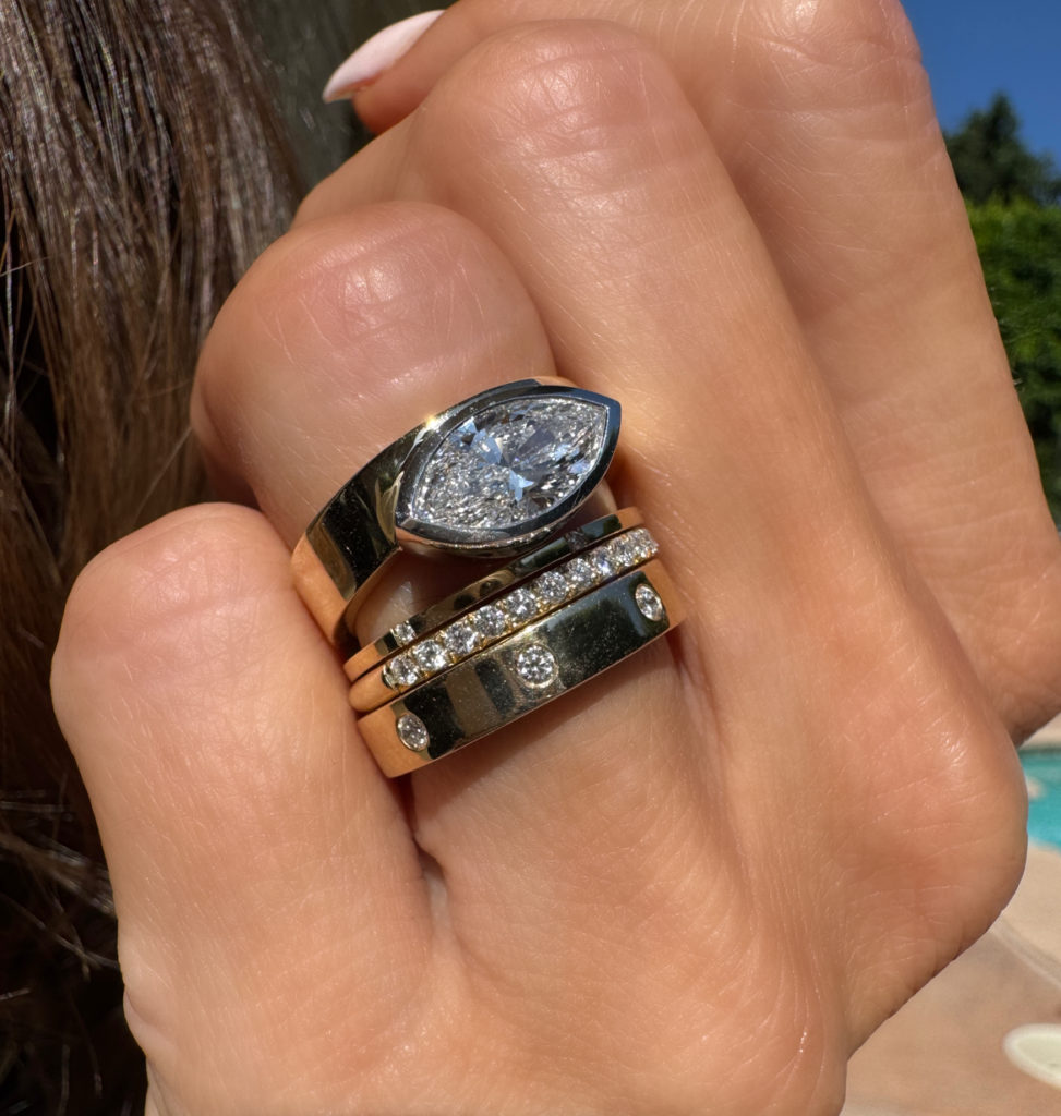 East-west marquise diamond ring stacked on hand with other gold and diamond bands 