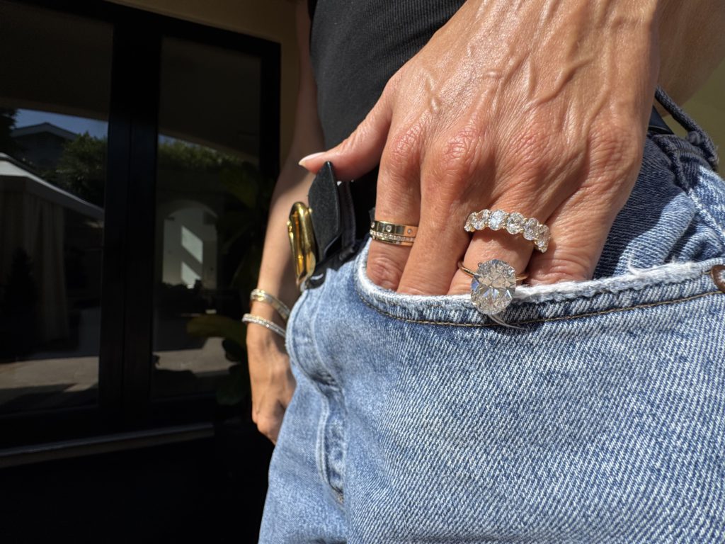 Stacked Diaomind rings peaking out of jeans on a hand 